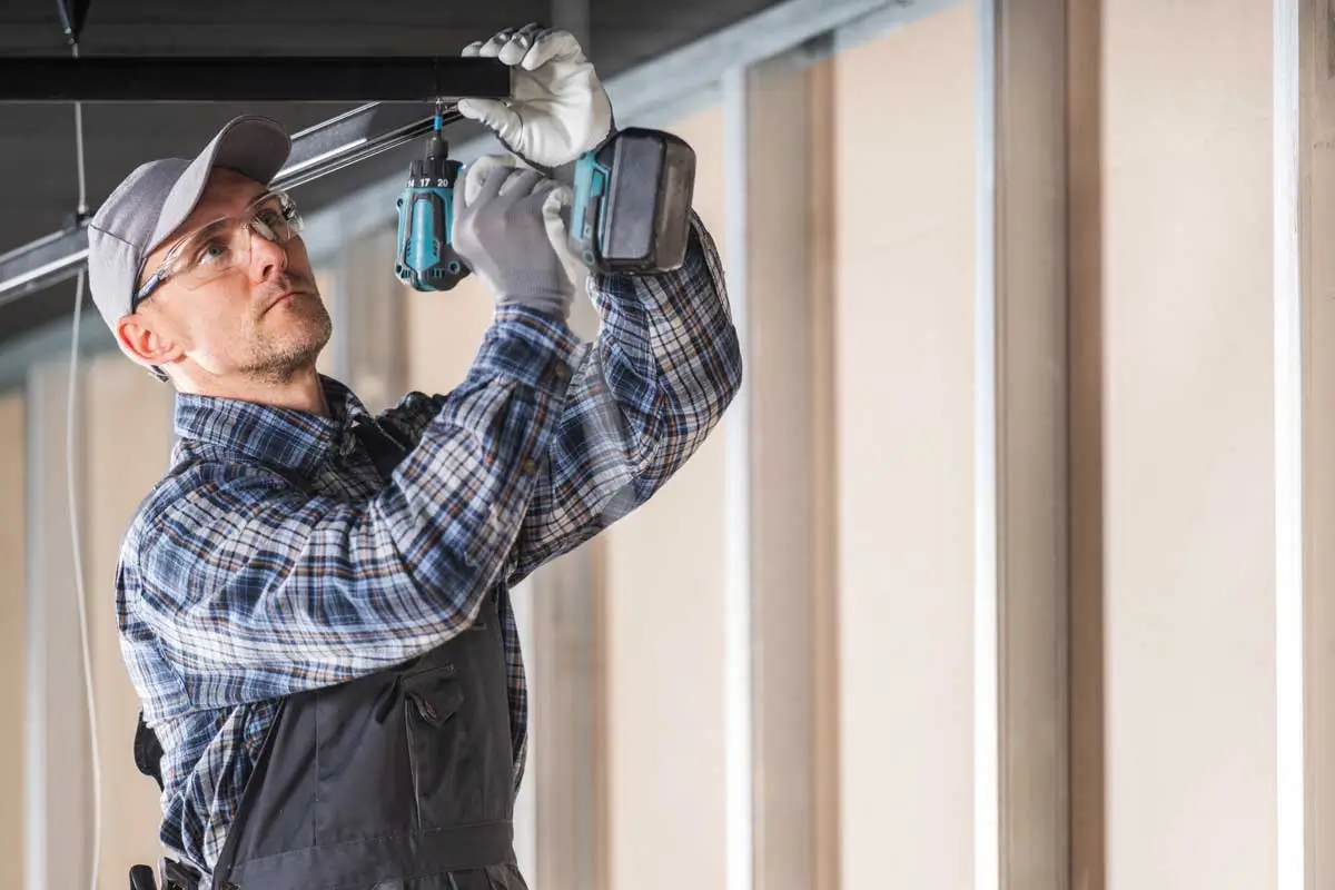 Skilled technician using power drill representing hands on experience supported by garage door business consulting