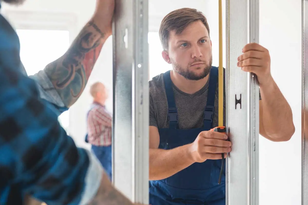 Technician measuring frame for installation reflecting planning and precision in garage door business consulting