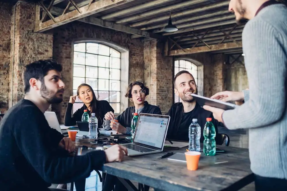 Creative team engaged in a strategy session about garage door marketing jobs in an industrial style workspace